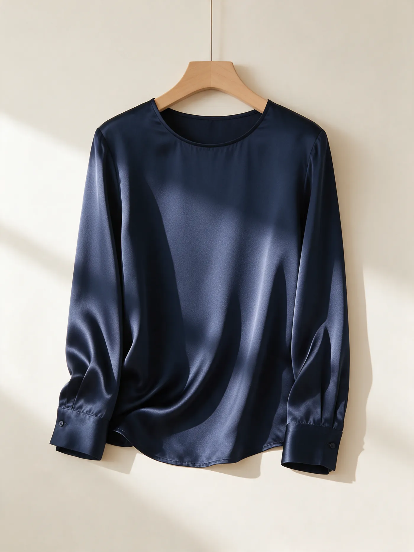 Packshot d'une blouse en satin bleu marine sur cintre en bois
